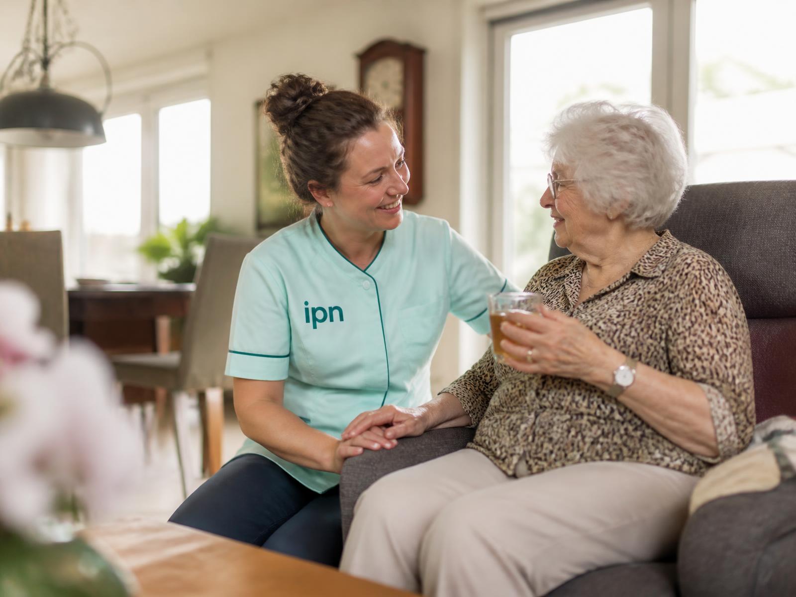 Zorgmedewerker in gesprek met een oudere cliënt thuis